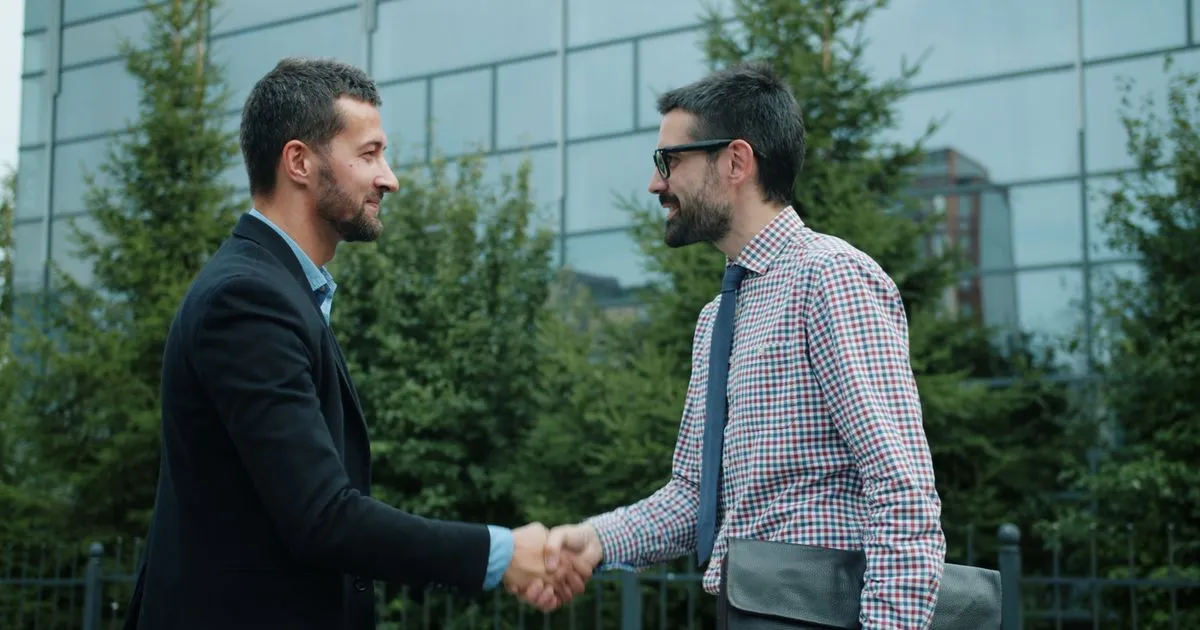 Business partnership handshake outside modern office