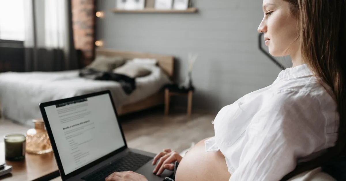 Pregnant professional working on a laptop before maternity leave