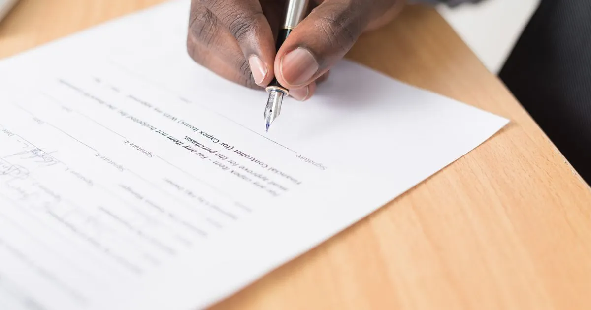 Hand signing a contract with a pen, worker classification review